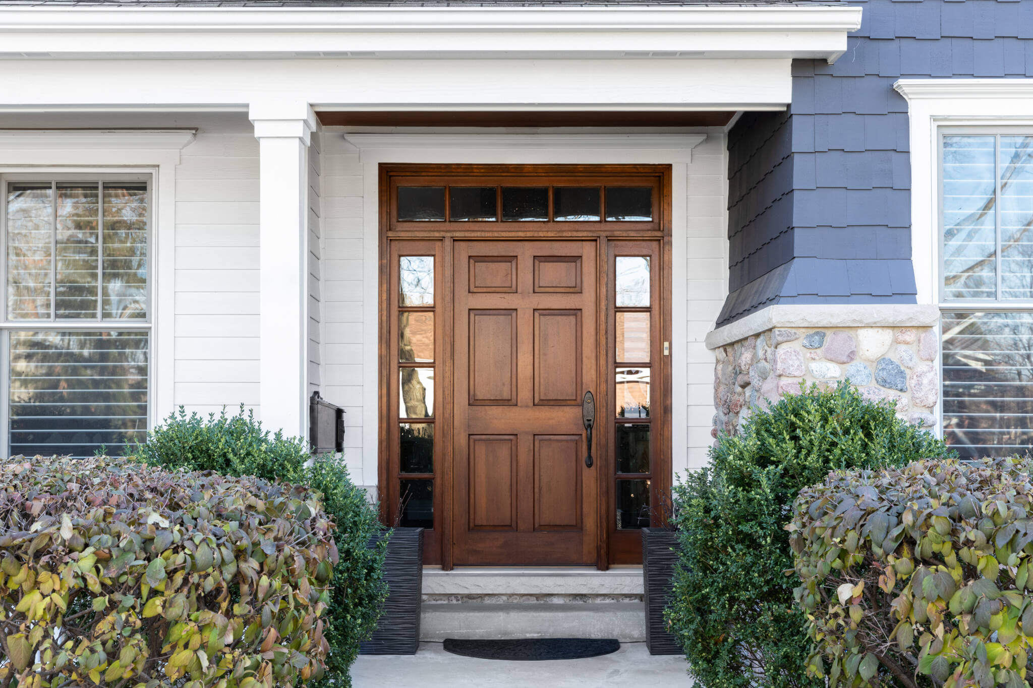 A Blue House With A Wooden Front Door.